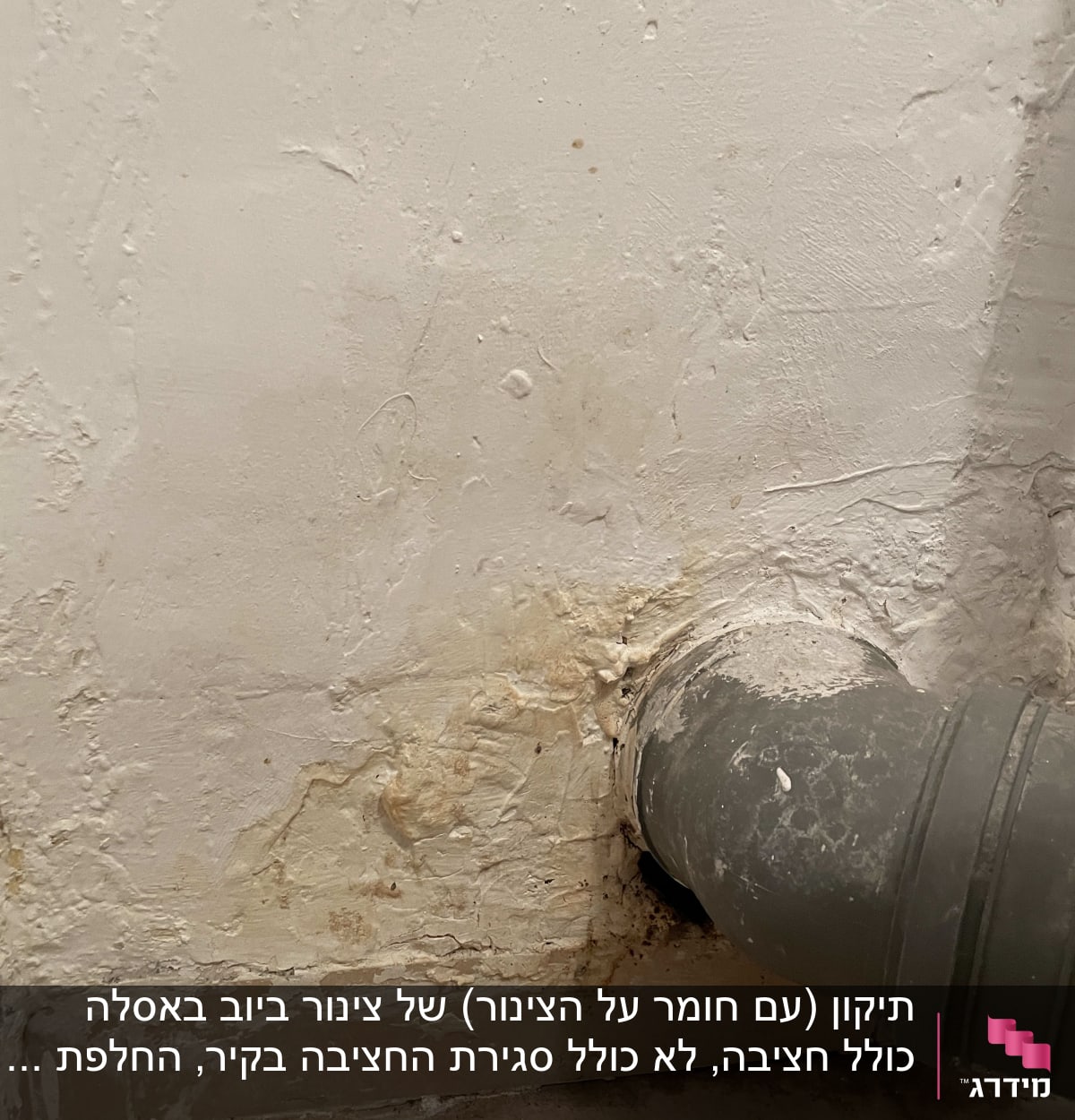 צינור אפור מחובר לקיר עם סימני רטיבות